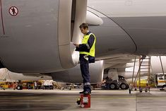 a man standing on top of a red box in front of a large jetliner