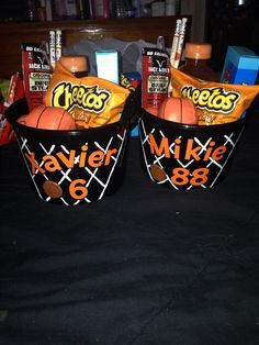 two baskets filled with candy and basketballs on top of a black cloth covered floor