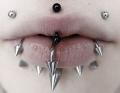 a woman's tongue with metal spikes attached to her lip and nose piercings