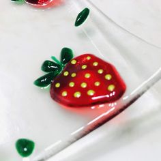 two glass strawberries sitting on top of a white table