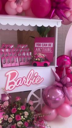 a pink candy cart with balloons and decorations