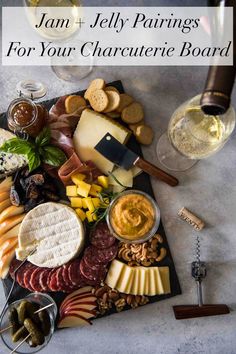 an assortment of cheeses, crackers, and wine on a slate platter