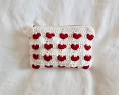 a crocheted red and white purse with hearts on it