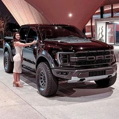 a woman standing next to a black truck