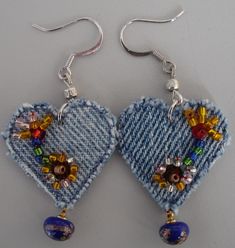 a pair of blue heart shaped earrings with beaded details and beads hanging from them