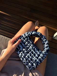 a woman laying on top of a wooden floor holding a blue and white handbag