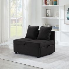 a living room with a black couch and bookcase on the floor in front of a window