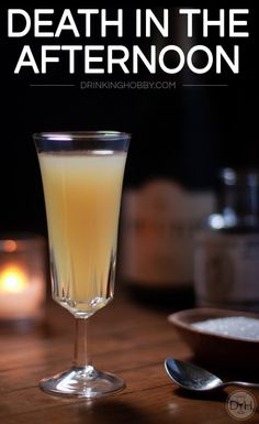 a glass filled with liquid sitting on top of a wooden table next to a candle