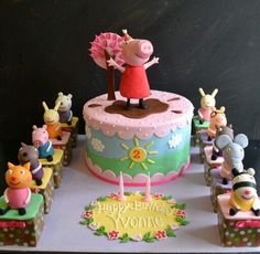 a birthday cake decorated with peppa the pig and other figurines on display