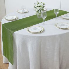 the table is set with white and green linens