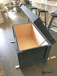 an open box sitting on top of a hard wood floor next to bar stools