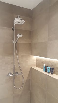 a shower head and hand held showerhead in a bathroom with beige tile on the walls