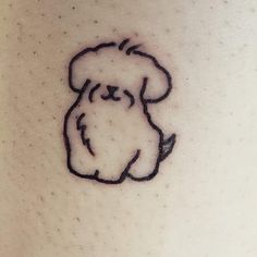 a small dog tattoo on the back of a woman's leg, it is black and white