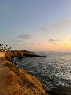 the beach is next to an ocean cliff and some houses are on top of it