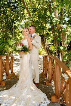 a bride and groom standing on a bridge