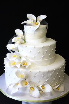 a three tiered cake with white flowers on top