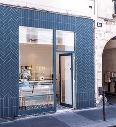 a store front with blue tiles and an open door on the side of the street