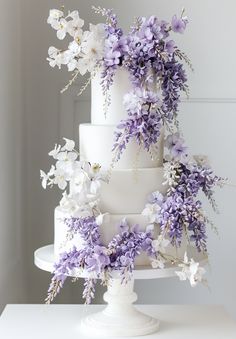 a three tiered white cake with purple flowers on top