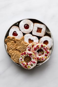 a metal bowl filled with assorted cookies and pretzels