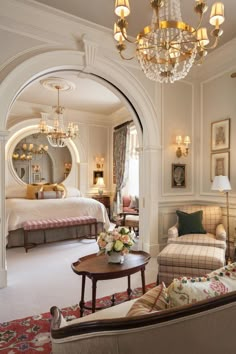 a living room filled with furniture and a chandelier hanging from the ceiling next to a bed