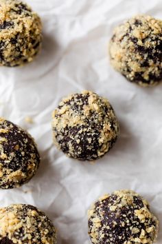 chocolate covered cookies sitting on top of a white sheet of wax paper with crumbs all over them