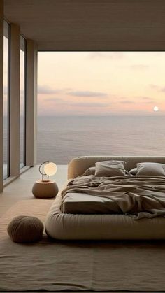 a large bed sitting in the middle of a bedroom next to a window with an ocean view