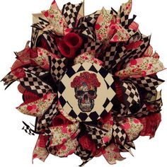 a wreath with a skull on it and red flowers in the center is decorated with black and white checkered fabric