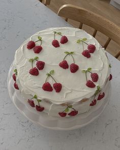 a cake with white frosting and raspberries on it sitting on a table