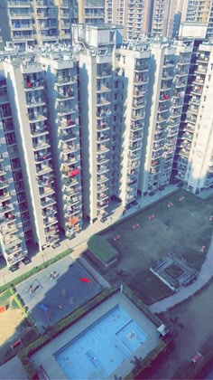 an aerial view of several apartment buildings with tennis courts in the foreground and swimming pool on the far side