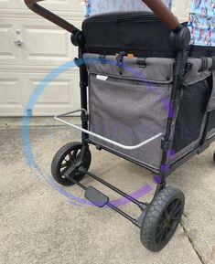 a baby stroller with wheels is shown in front of a garage door and has an umbrella attached to it