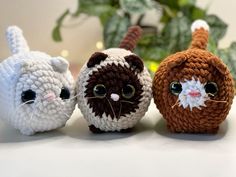 three small crocheted cats sitting next to each other on a white counter top