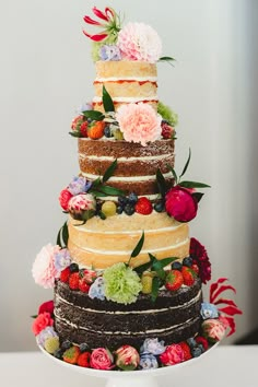 a multi layer cake decorated with flowers and berries