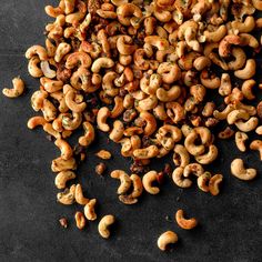 a pile of cashews sitting on top of a black counter next to a knife