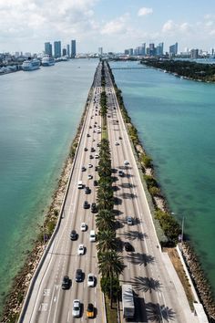 an aerial view of a highway with palm trees on both sides and the ocean in the background