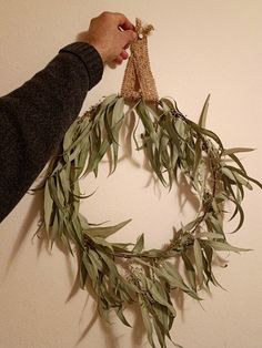 a person holding a wreath made out of leaves and twine with a burlock