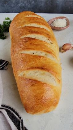 a loaf of bread sitting on top of a cutting board next to garlic and parsley