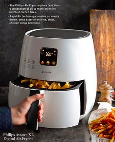 a person is holding a knife over french fries in front of an air fryer