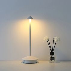 a white table lamp sitting next to a vase with flowers