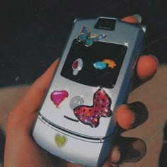 a person holding a cell phone with stickers on it