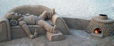 a sand sculpture sitting on top of a sandy beach next to a fire place in the sand