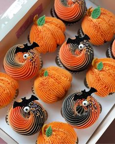 cupcakes decorated like pumpkins with black and orange icing in a box