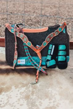 a black and blue purse sitting on top of a dirt ground next to a fence