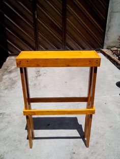 a wooden stool sitting on top of a cement floor