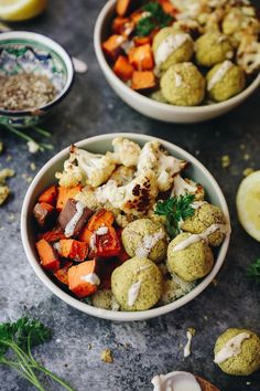 two bowls filled with different types of food next to lemon wedges and parsley