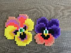 two pieces of perler bead art sitting on top of a wooden table