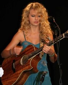 a woman in a blue dress playing an acoustic guitar