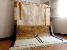 a white and brown rug sitting on top of a wooden floor next to a window