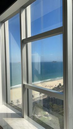 an open window looking out at the beach and ocean from a room with large windows