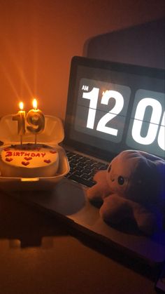 a laptop computer sitting on top of a desk next to a birthday cake with candles