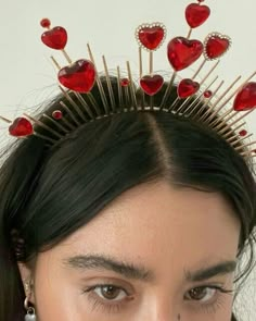 a woman wearing a crown with red hearts on it's head and pins in her hair